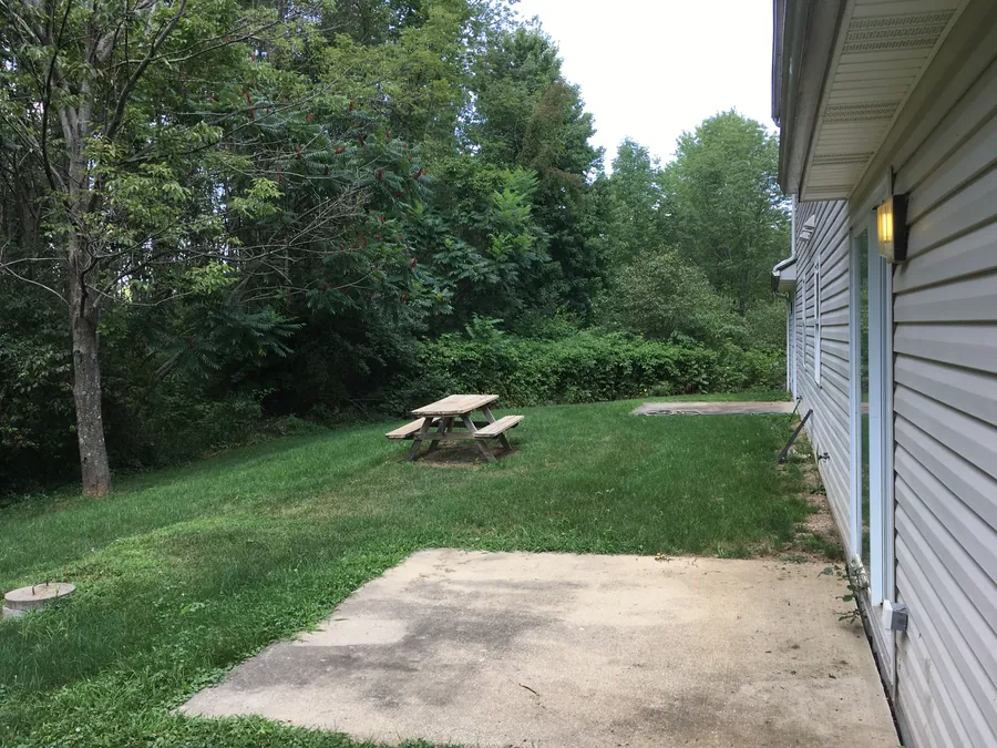 A patio and picnic table on a wooded lawn at Hidden Pines